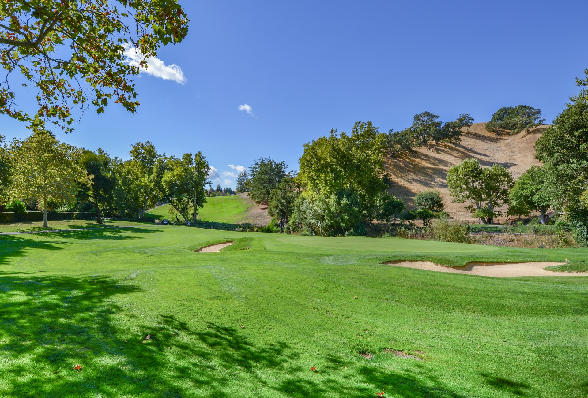 Golf fairway with bunkers under open sky.